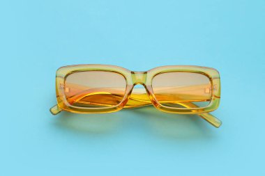 Mavi arkaplanda şık sarı güneş gözlükleri