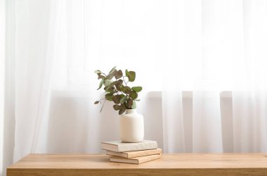 Okaliptüs dallı kitap ve vazolar odanın penceresinin yanındaki masanın üzerinde, yakın plan.