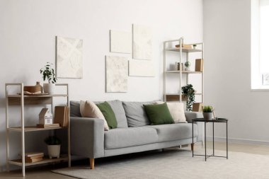 Gri kanepe, masa ve raf üniteleriyle oturma odasının içinde.