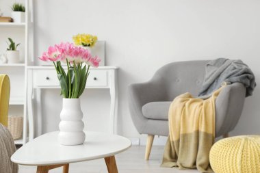 Aydınlık oturma odasındaki masada laleli vazo.