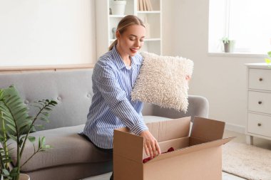 Evdeki kutudan yastık alan genç bir kadın.