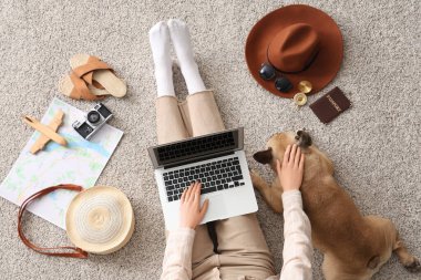 Dizüstü bilgisayarı olan genç bir kadın, sevimli bir Fransız bulldog ve evde gezici aksesuarlar.