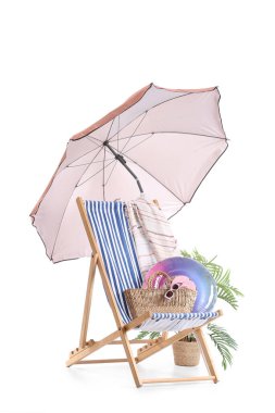 Plaj şemsiyeli çizgili güverte sandalyesi ve beyaz arka planda izole edilmiş seyahat aksesuarları.