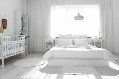 Yatak, beşik ve bebek kıyafetleriyle aydınlatma odasının içinde.