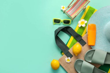 Turkuaz arka planda limonlu ve plaj aksesuarlı yaz kompozisyonu