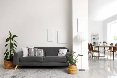 Oturma odasında siyah kanepe, bitki ve yemek masası var.