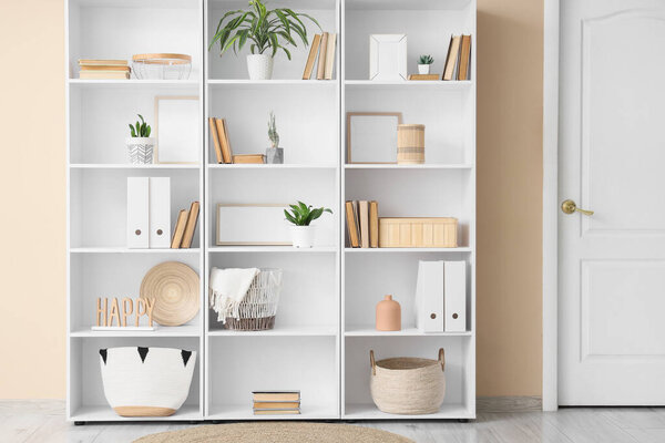 Bookshelf with decor and plants near beige wall in room