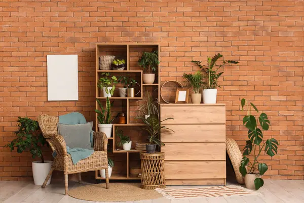 Raflama ünitesi, farklı ev bitkileriyle dolu çekmeceler ve odasındaki tuğla duvarın yanındaki koltuk.