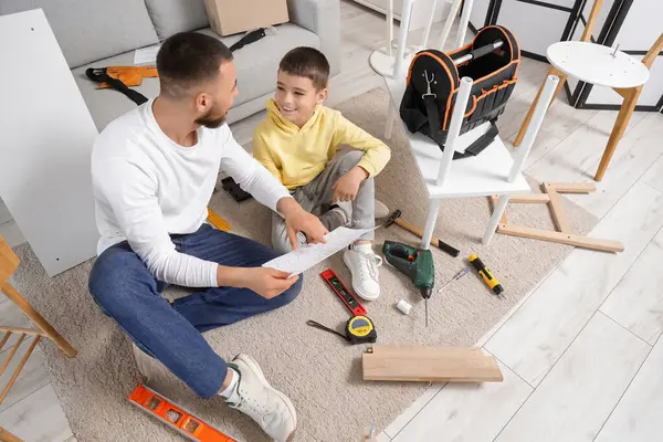 Babası talimatlarla ve oğlu evde mobilya montajı yapıyor.