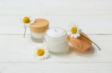 Kavanozlar dolusu papatya çayı ve beyaz ahşap arka planda çiçekler.