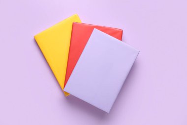 Leylak arkaplanı üzerine renkli kitaplar