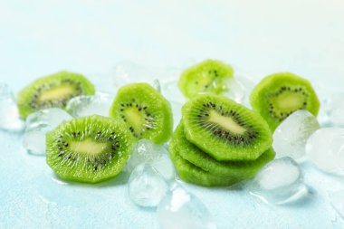 Açık mavi arka planda taze kivi dilimli buz küpleri, yakın plan.