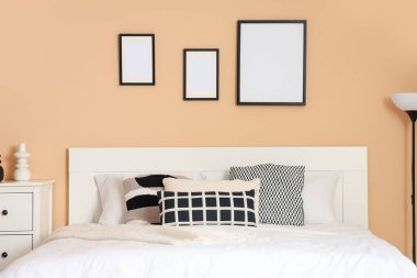 Odadaki bej duvarda büyük yatak ve boş çerçeveler.