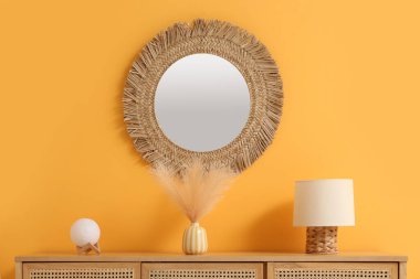 Çekmeceler, lambalar, dekoratif tüylü vazo ve odanın içinde yuvarlak ayna, yakın plan.