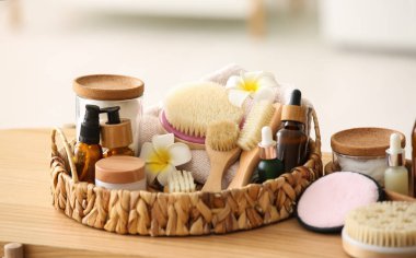 Ahşap masa üzerinde farklı spa aksesuarları ve kozmetik ürünleriyle hasır tepsi.