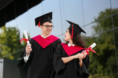 Üniversiteye yakın diplomalı bir çift mezun öğrenci.