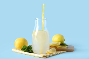 Mavi arka planda nane ve limonlu bir şişe taze limonata.