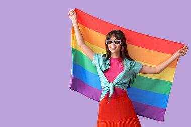 Güneş gözlüklü, leylak arkaplanda LGBT bayrağı olan güzel bir kadın.