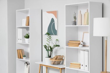 Kitap rafları, masa ve bitkilerle aydınlatma odasının içinde.