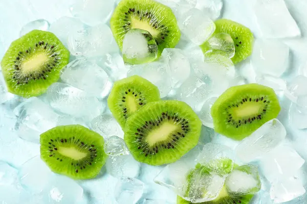Açık mavi arka planda taze kivi dilimli buz küpleri