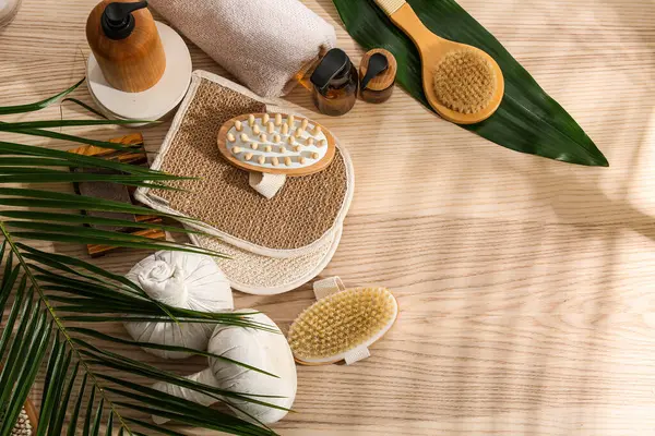 Farklı spa aksesuarları, kozmetik ürünleri ve ahşap masa üzerinde palmiye yaprakları olan kompozisyon