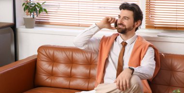 İş adamı ofiste cep telefonuyla konuşuyor.