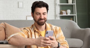 Evde cep telefonu kullanan yakışıklı bir adam.