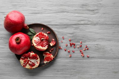 Taze olgun narlar ve gri ahşap arka planda tohumlarla dolu bir tabak.