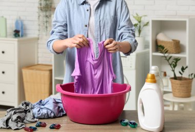 Genç bir kadın evdeki plastik havuzda çamaşır yıkıyor.