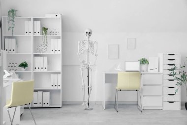 Masada insan iskeleti modeli ve modern dizüstü bilgisayarı olan hafif bir hastane.