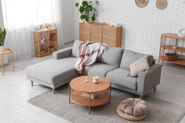 Oturma odasının içinde rahat gri kanepe, puf ve masa, yakın çekim.