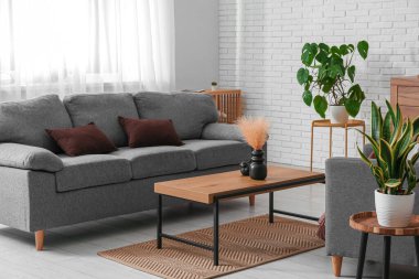 Oturma odasının içinde rahat gri kanepe ve masa, yakın plan.