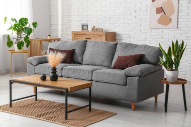 Rahat gri kanepesi ve masaları olan oturma odasının içinde, yakın plan.