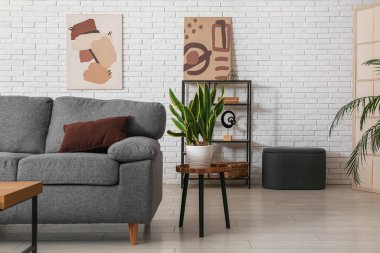 Rahat gri kanepesi, masası ve çiçeğiyle oturma odasının içinde. Yakın plan.