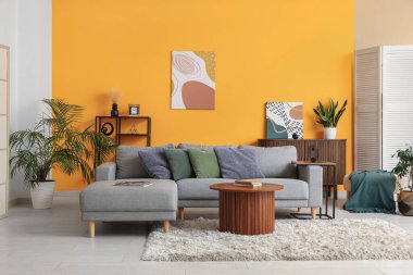 Sarı duvarın yanında rahat bir kanepe ve kahve masası olan oturma odasının içinde.