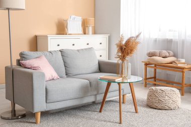 Gri kanepe ve vazo, oturma odasının iç tarafındaki masada çimen, yakın plan.