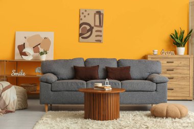 Oturma odasının içinde rahat bir kanepe, masa ve puf.