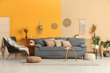 Rahat gri kanepe, puf ve masa aydınlık oturma odasının içinde.