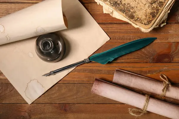 Ahşap zemin üzerinde kalem, mürekkep ve parşömen kağıtları.