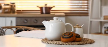 Mutfaktaki masada lezzetli haşhaşlı çörekler ve bir kavanoz şeker.