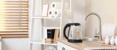 Mutfaktaki lavabonun yanında suyu olan elektrikli çaydanlık.