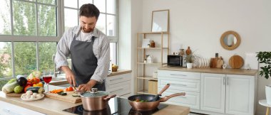 Mutfakta sebze kesen yakışıklı sakallı adam.