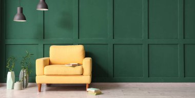 Yeşil duvarın yanında şık bir koltuk, lambalar ve bambu.