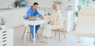 Kan şekerini ölçen tükenmez kalemli erkek endokrinolojist klinikteki kadın hasta.