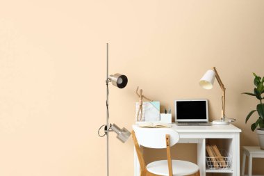 Modern dizüstü bilgisayarı ve renk duvarına yakın kırtasiyesi olan şık bir iş yeri