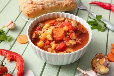 Yeşil ahşap arka planda bir kase lezzetli biftek yahnisi.