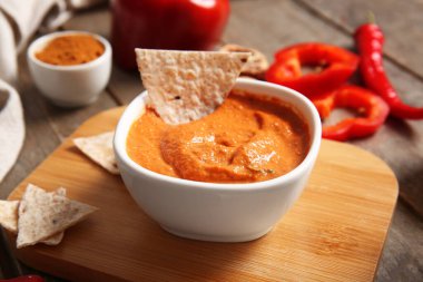 Tahta arka planda bir kase lezzetli muhammara ve pide.