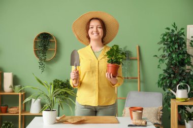 Hasır şapkalı, çiçekli, bahçe malalı, rahat yeşil odalı mutlu kadın.