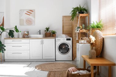 Çamaşır makinesi ve bitkileri olan şık bir çamaşırhane.