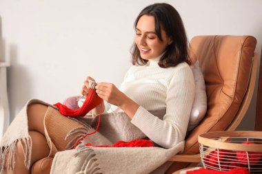 Evde iğneli çorap ören genç bir kadın.